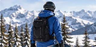 Snowboarder in a blue jacket and black backpack looking at the mountains, ready to carry a snowboard to the lift