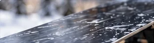 Close-up of a waxed snowboard base and the steel edge along its side, the part you file when you sharpen snowboard edges