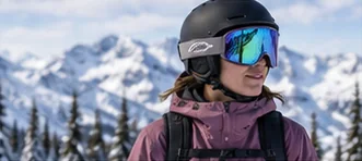 Snowboarder wearing a helmet and mirrored snowboard goggles on the mountain