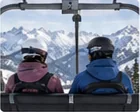 Two snowboarders riding a chairlift