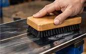 Brushing a waxed snowboard base from tip to tail